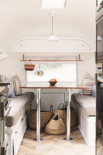 The dining space is located at the front of the trailer. The chevron flooring is Oak Fortress Rochesta by Kaindl and the upholstery is by Joybird.