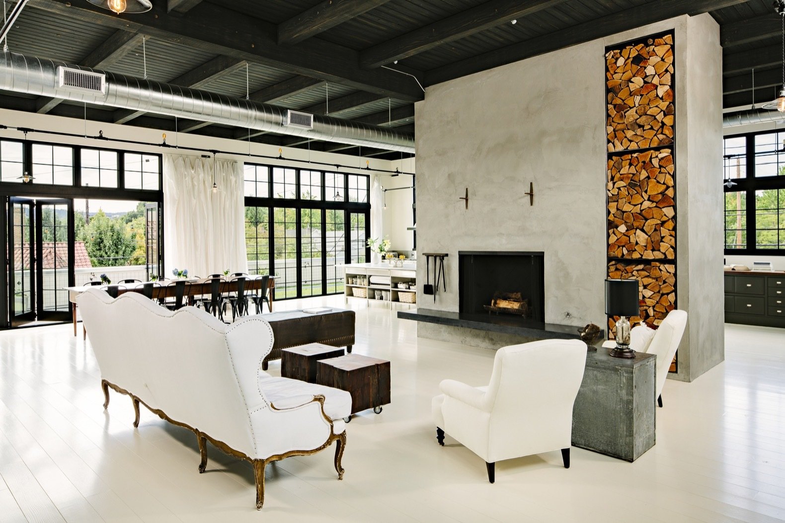 A massive concrete hearth, placed just off center, anchors the living room. The Douglas fir floors have been painted a creamy white.