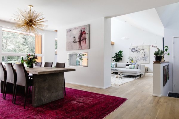 Walls were knocked down to connect the living room and dining area, while a see-through fireplace partitions the rooms. The bright fuchsia rug was a vintage find.