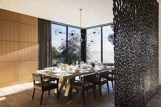 A custom bronze divider by artist Michele Oka Doner screens the formal dining room from the entry. The chandelier is by Lindsey Adelman Studio.