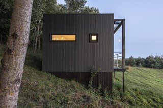 The exterior is clad in fiber-cement panels and topped with a bitumen roof.