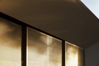 A series of sliding, perforated, bronze screens let in dappled light while providing privacy and protection from the sun.