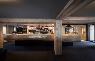 A gigantic fir tree trunk serves as the bar counter, providing a connection to the outdoors. The bar lights are by Spanish company Marset.