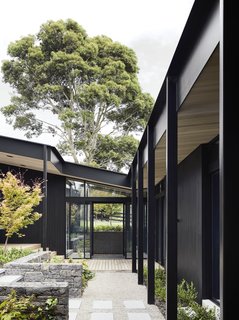 "Three elongated blackened timber pavilions form a U shape, encompassing the external courtyard and identifying strongly with the site narrative and notions of a working yard or arena," the architects explain.