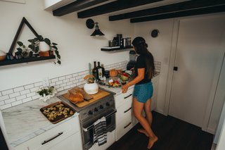 The galley kitchen features a range/oven on one side and the sink and fridge on the other. The bathroom is behind the door next to the kitchen. 