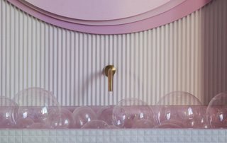 The bathtub is covered in pyramidal glass mosaic and filled with balls resembling giant soap bubbles.