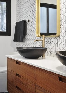 The renovation introduced new plumbing and lighting fixtures selected by NMT Financial, custom wood vanities designed by See Arch, and new tiled walls installed in all bathrooms.