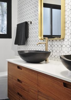 The renovation introduced new plumbing fixtures, lighting, custom wood vanities, and tiled walls in the bathroom.