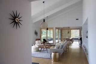 For a greater sense of flow, the wall that once divided the living room from the dining area was removed and replaced with oak slats. The tongue-and-groove wood on the vaulted ceiling and walls were repainted, while the floors were replaced with wide plank oak harvested and milled locally.