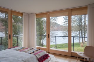 The largest guest bedroom is surrounded by walls of glass framing views of Candlewood Lake.