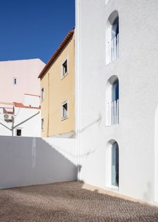 The south side of the house opens up to an outdoor patio lined with Portuguese calçada paving.