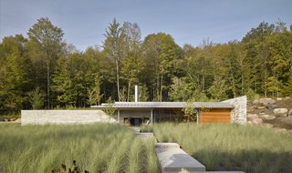 A zigzagging path built of locally sourced Stanstead granite leads throughs a field of grasses to the Pool House.