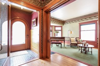 Fitted with original flooring and paneling, the light-filled vestibule includes a large curved door with beveled glass and a large swinging door that leads to the foyer.