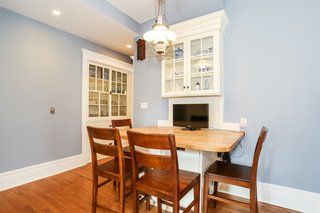The remodeled breakfast room comes with a built-in table with a display cabinet and six chairs. The built-in hutch in the corner is original to the home. The renovation converted the antique kerosene fixture to run on electricity.
