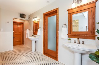 The master bath features reproduction tile floors with radiant heating, two pedestal sinks, a Kohler commode, and (not pictured here) a large steam shower with a ceramic tile surround and built-in bench.