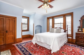 The beautiful second bedroom in the southwest corner of the home has an original fireplace and windows with leaded glass panels.