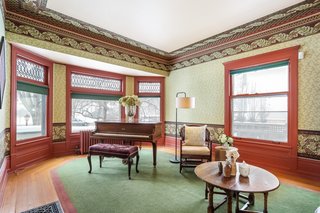 The living room overlooks the street with a large bay window with original leaded glass panes. The original hardwood floors include an exterior oak border and an inner area of pine (covered by the rug, which comes with the home).