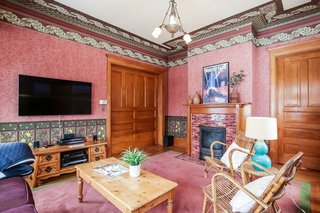 A wood-burning fireplace with a tile surround and wooden mantel anchors the family room. Note the sliding pocket door (one of many in the home) that leads to the foyer.
