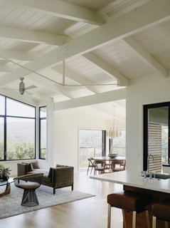 The architects preserved the existing beamed ceilings, which give the open-plan living area an airy feel. The living area is dressed with a vintage tête-à-tête sofa by Edward Wormley, a Warren Platner chair, and an Isamu Noguchi table.