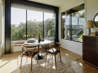 Beneath the dining area is a small sitting room flooded with light from three sides through bronze anodized windows with automatic translucent shades by Fleetwood Windows & Doors.