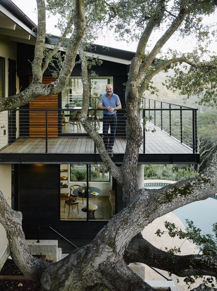 Malcolm Davis stands behind the specimen oak tree on the new cantilevered wraparound deck.