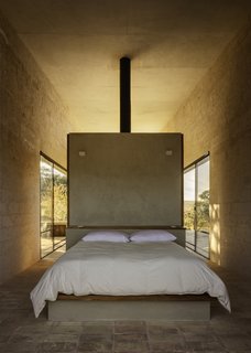 Clay tile floors and timber surfaces tie the building to the land. The locally quarried stone walls are left exposed in the interior.