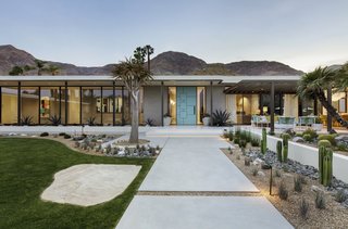 Poured concrete walkways flanked by desert landscaping lead to the architect-designed front door painted bright blue.