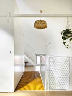 Upstairs, the "parents' retreat" includes a centrally located bathroom "box," seen on the left of the image. The bright orange walkway is perforated to let natural light pass through.