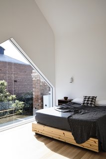 Bathed in west-facing light, the master bedroom includes a large window (also created in the shape of the roof) with views of the rear garden.