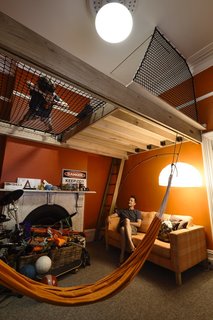 The front of the terrace now houses a guest bedroom and (pictured here) the teenage son's bedroom. Taking advantage of the high ceiling, the architects added a suspended platform bed space, a lounging net, and a hatch that leads up to a "secret" roof space.