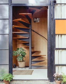 Illuminated by a skylight, the spiral staircase ascends to the bedroom level.