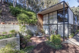 Pictured is the south court partly sheltered by the roof overhang. Note the rear wood panel wall that creates a continuation from the interior to the exterior. Ray used the exposed concrete planter for growing flowers.