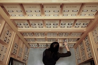 The products are stored in natural wood boxes that live in a glass-walled, humidor-style display case.