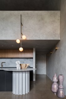 This Brutalist Australian apartment was inspired by a concrete bunker, with the marble kitchen countertops and backsplash helping to elevate itspared-down look. 