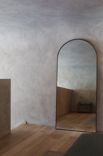 The rounded shape of the mirror matches the curves in the ceiling.