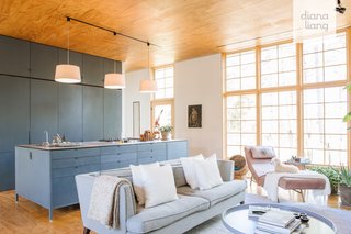 Tinted radiata pine panels wrap the light-filled living area, which is furnished with a Spectra Home Furniture sofa, a leather lounger, and an Overstock rug. In the kitchen, Hygge paired their custom cabinets with Bosch appliances.