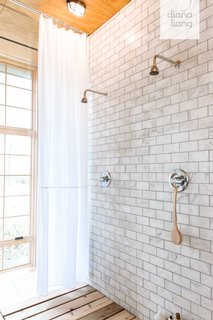 The showers are lined with Carrara subway tile from TheBuilderDepot and a wooden slat floor.