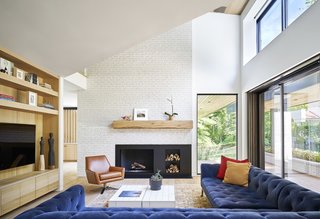 An indigo-velvet Restoration Hardware Chesterfield sectional anchors the living room located in the heart of the home.