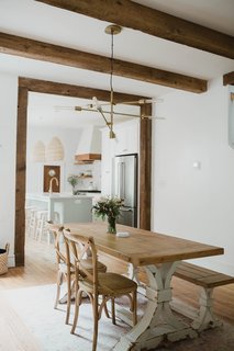 Chris and Claude Beiler tore down the wall that divided the kitchen and dining room. A West Elm light fixture hangs over the dining table; reclaimed timber ceiling beams and trim lend a sense of warmth to the interior.