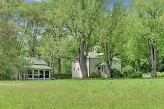 On the left, the two-story guest cottage is fronted by a screen porch with a view of the meadow. On the right is the old barn building that's been repurposed into a garage with an office.