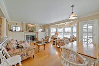 The family room is anchored with a fireplace on one side and a breakfast table on the other. Two glazed doors to the rear deck flank the large window seat.