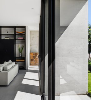 Black aluminum door frames stand out against the concrete structure and sandblasted marble floors.