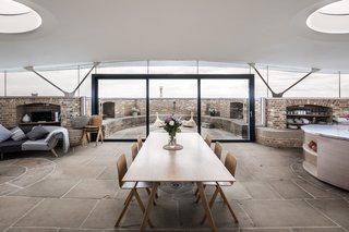 The top floor of the fort has been turned into an open-plan living room, dining area, and kitchen protected by an undulating plywood roof providing 360-degree views of the surroundings.