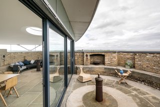 Full-height sliding glazed doors open up to an outdoor terrace on the exposed section of the battlements with spectacular views.