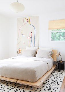 A mix of colors and textures adds character to this bedroom that features a Floyd bed frame, Wright mattress and bedding, a HAY side table and Aelfie rug and tapestry. 