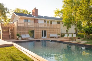 The backyard features a large pool with a mahogany wrap-around deck and the Perch Sofas and coffee table from Blu Dot's new outdoor furniture collection. 