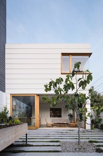 “The custom profile painted siding echoes the typical horizontal lap siding seen throughout the neighborhood while playing with scale,” says Ryan. “Also, the extruded white oak window boxes on the new structure give a nod to the more traditional approach to window casings while making them more three dimensional.”