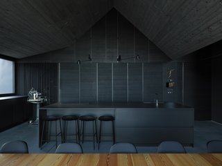 The dark kitchen creates a bold visual contrast with the nearby cirmolo wood wall. The kitchen countertops are slate, and the cabinets are dark gray-painted European oak.