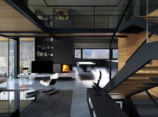 A glass-walled bridge links the master bedroom with the office on the upper floor. The layout creates a double-height space for the living area and keeps the drama of the exposed concrete ceiling visible from the ground floor.