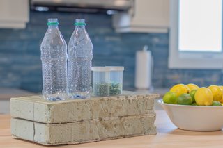 Pictured are two plastic bottles next to capsules containing recycled PET pellets and mulch. Armacell, a company <span style="font-family: Theinhardt, -apple-system, BlinkMacSystemFont, "Segoe UI", Roboto, Oxygen-Sans, Ubuntu, Cantarell, "Helvetica Neue", sans-serif;">Saulnier</span><span style="font-family: Theinhardt, -apple-system, BlinkMacSystemFont, "Segoe UI", Roboto, Oxygen-Sans, Ubuntu, Cantarell, "Helvetica Neue", sans-serif;"> is familiar with due to his work in boatbuilding, transforms the pellets into hardened foam that is used as the core of JD Composite's structurally insulated panels.</span>